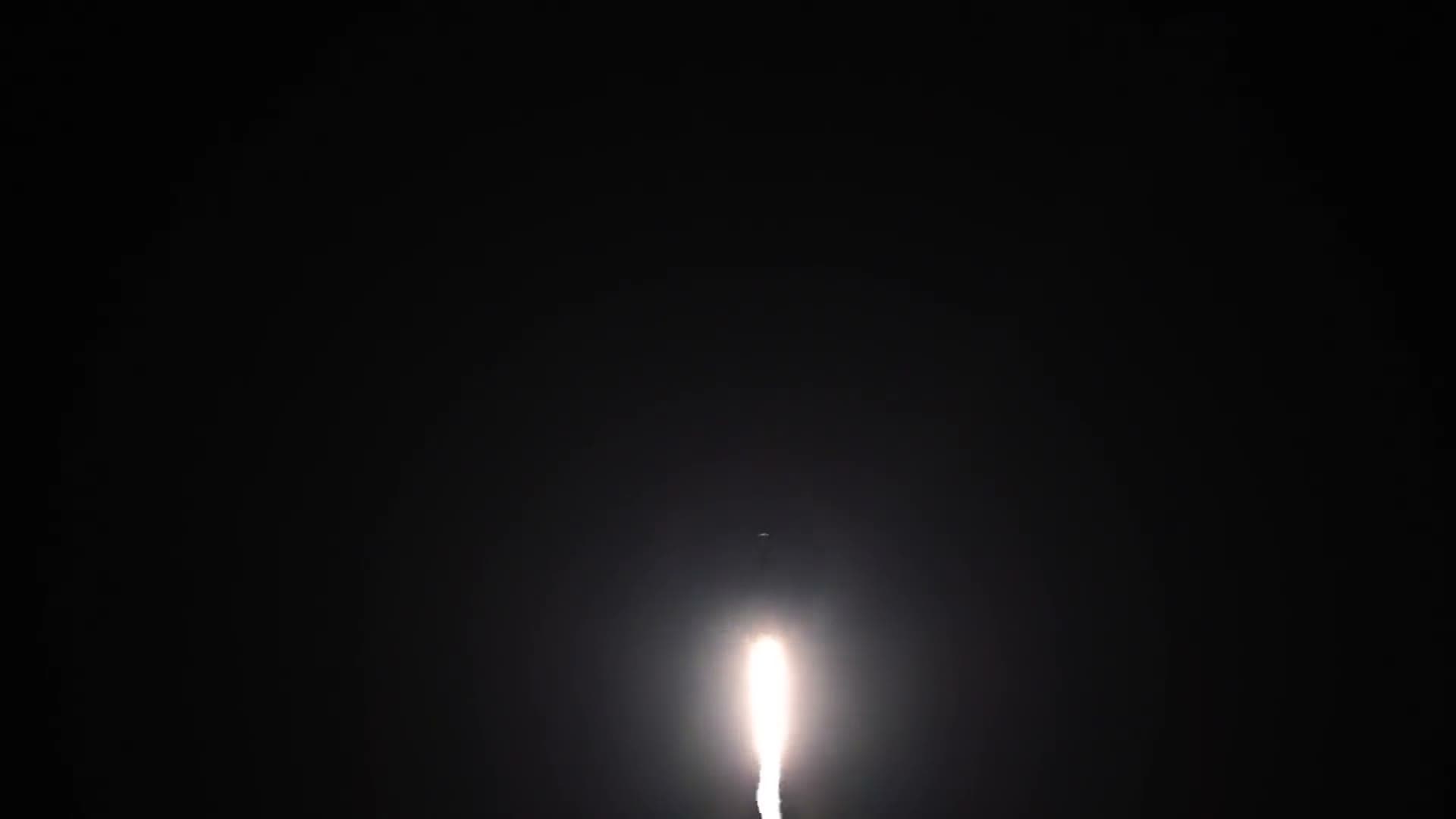A rocket's engine glow climbing through a dark night sky
